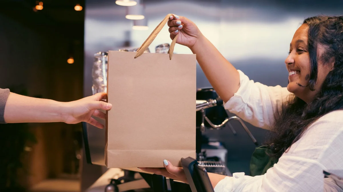 Customer collecting a local pickup order from a staff member at a shop counter