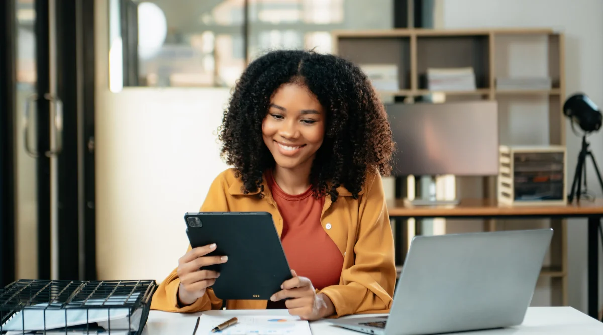 Smiling woman using tablet at desk