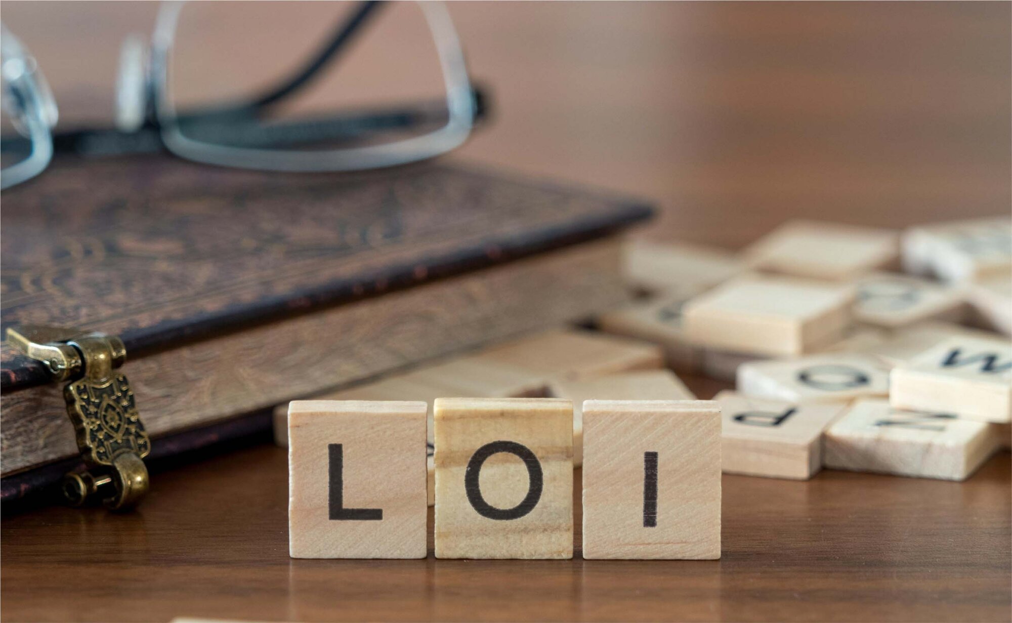 An image of LOI wooden blocks along with a book and spectacles.