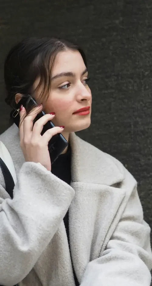 A headshot of an adult woman on the phone ensuring her financial accounts and work records are updated after a legal name change