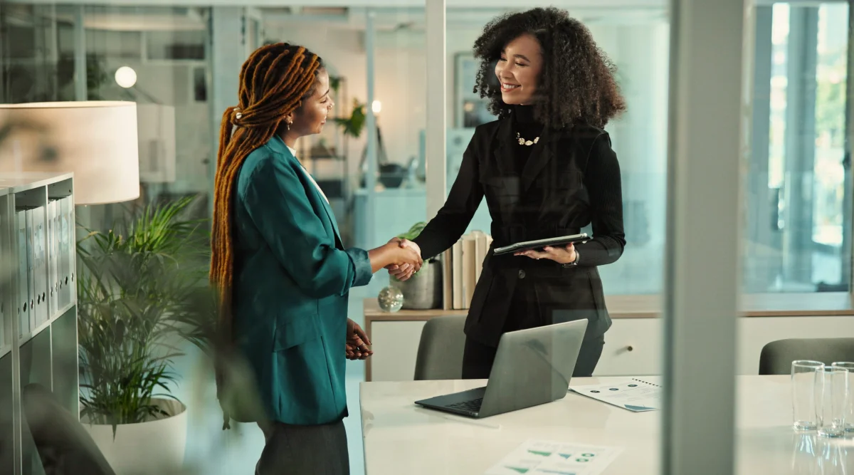 Two professionals shake hands in a bright office setting