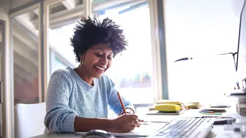 A lady smiling and writing on her notepad.