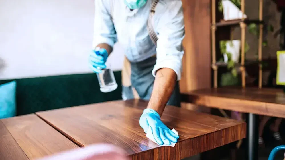 A N.Y. restaurant owner and single-member LLC cleans off a table. Disadvantages of an N.Y. LLC include higher sales taxes, higher state taxes, and high startup fees.