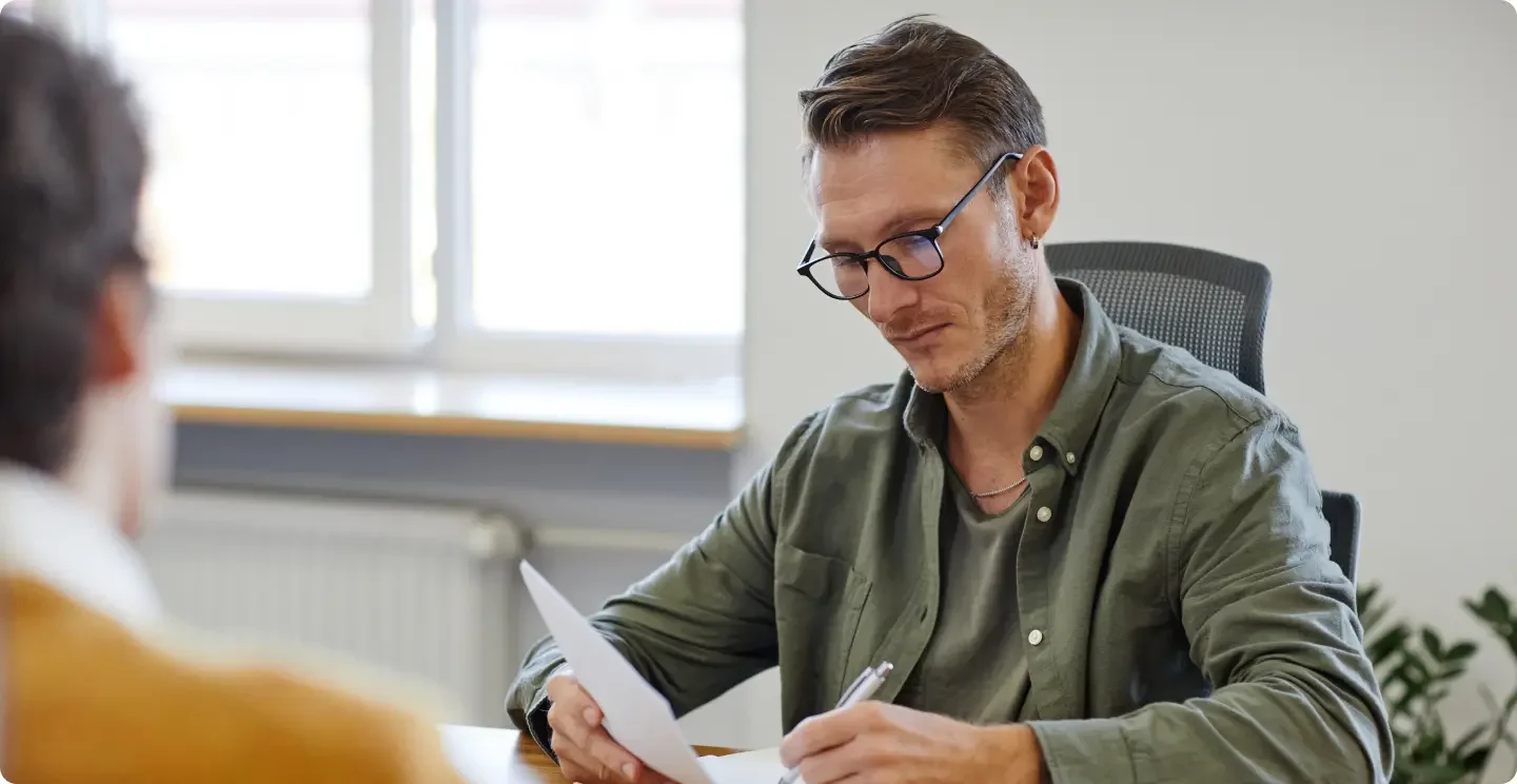 Brunette White man with a 5 o'clock shadow and glasses wearing a green button up shirt on top of green t-shirt filling out the dissolution paperwork that he received from LegalZoom.
