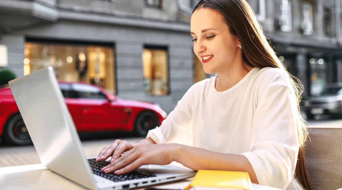 Smiling woman typing on laptop outdoors