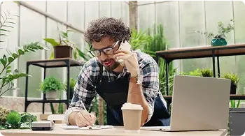 Man with brown hair surrounded by plants works on legal documents 