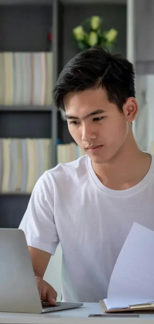 An adult man sitting at a desk in front of a laptop researching what documents you're required to update as part of a legal name change