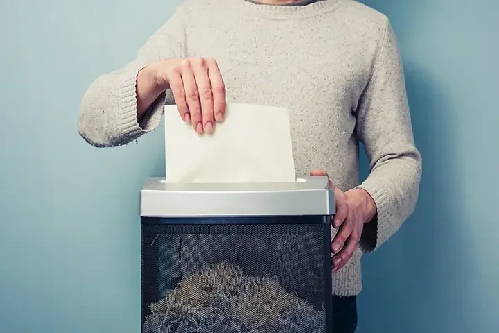 A person is adding a document to the shredder. 