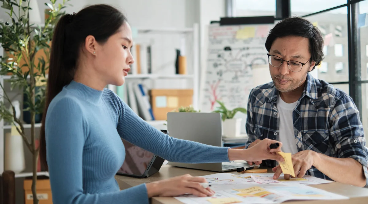 A man and a woman talking to each other while reviewing documents.