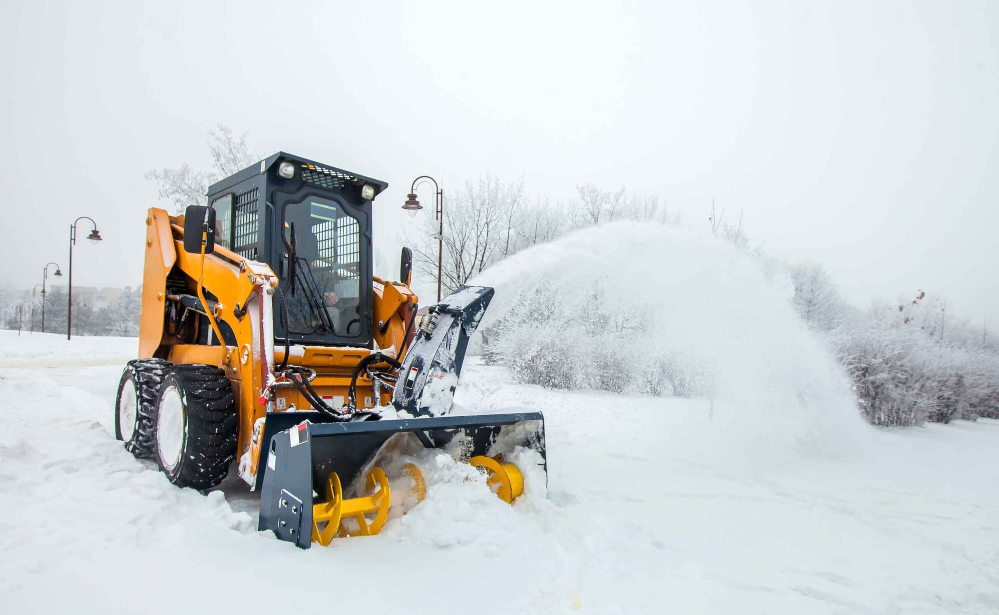 An image of a snow removal truck clearing snow off a pathway.