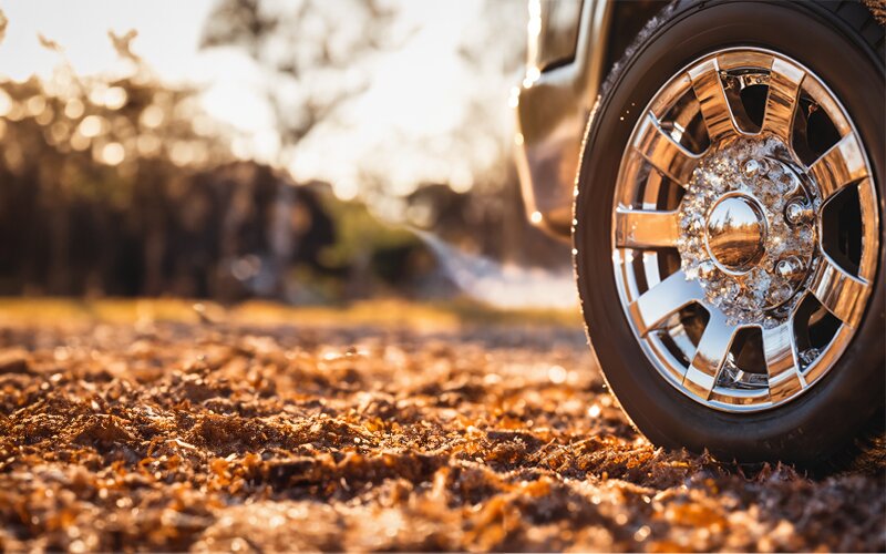 An image of a car's tire and wheels during sunset.