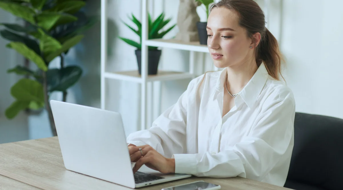 Woman in white shirt typing on laptop