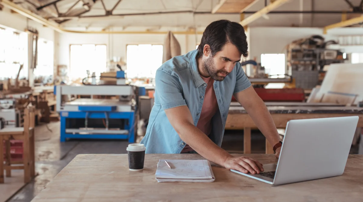 A man stands in his workshop and reviews his patent on his workshop.