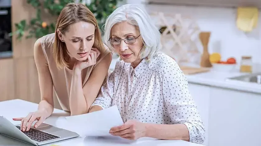 An elderly woman and her daughter are looking over paperwork.