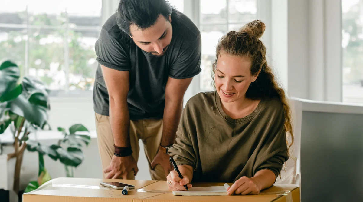 Woman writing on a box with a man observing