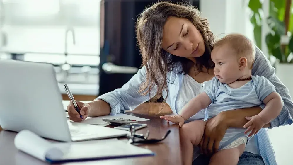 Mother working from home with her baby on her lap.