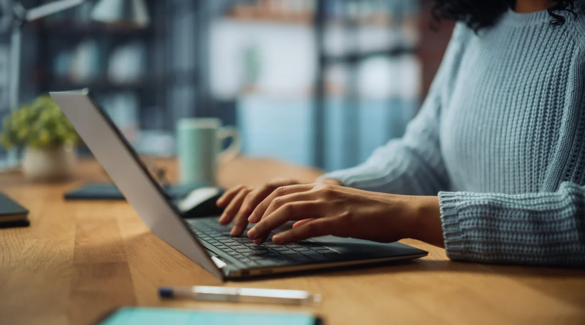 Close up of a woman's hands as she types on a laptop casually in a coworking space.