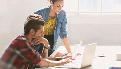 Three coworkers discussing business plans around a computer laptop