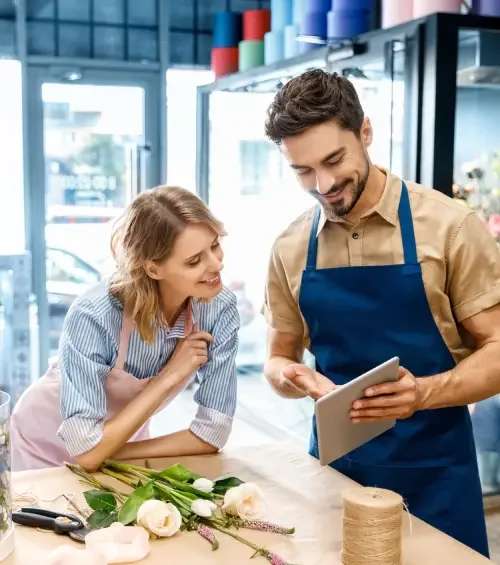 A man in a florist shop showing his business partner the employment agreement template an attorney created for him on a tablet