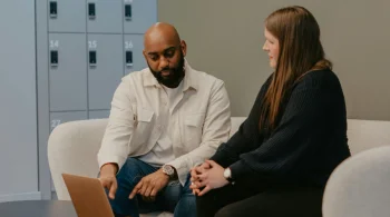 Man pointing at laptop while discussing with woman