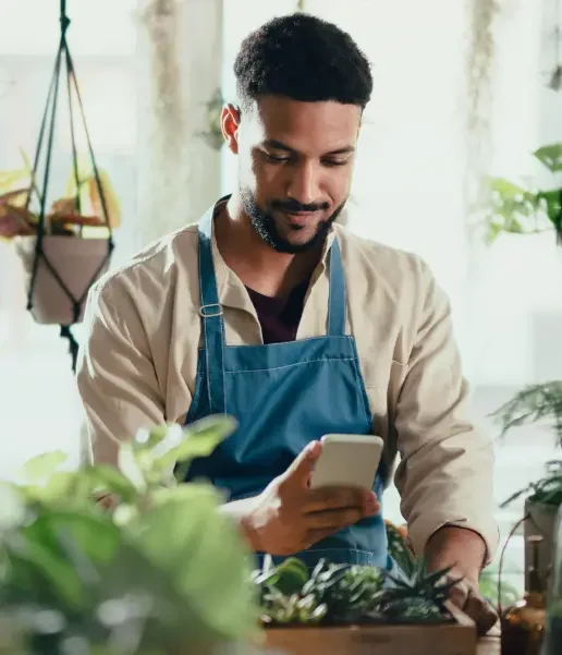 A man working at a garden shop using his smart phone.