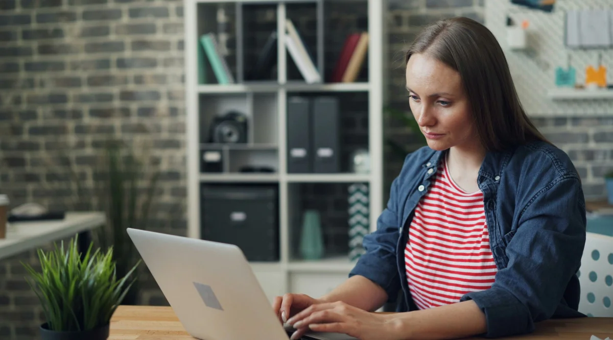 Woman in striped shirt typing on laptop