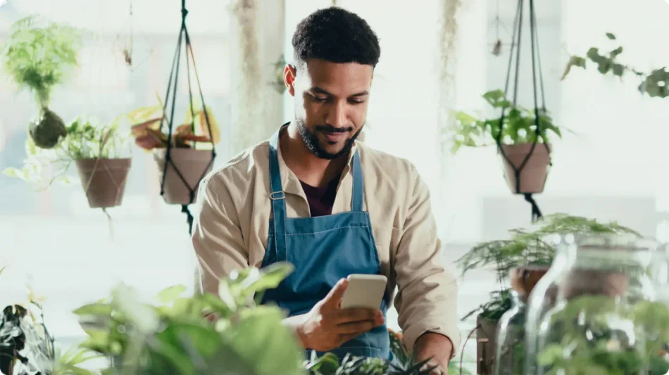 A man working at a garden shop using his smart phone.