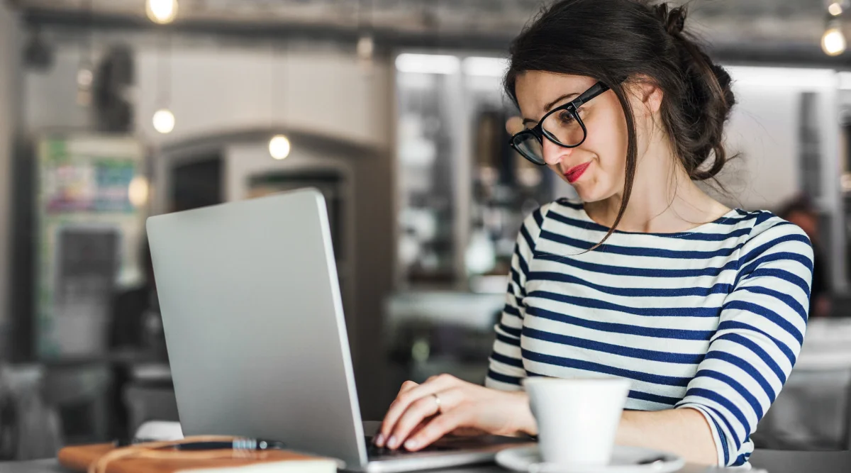 Woman in stripes using laptop with coffee