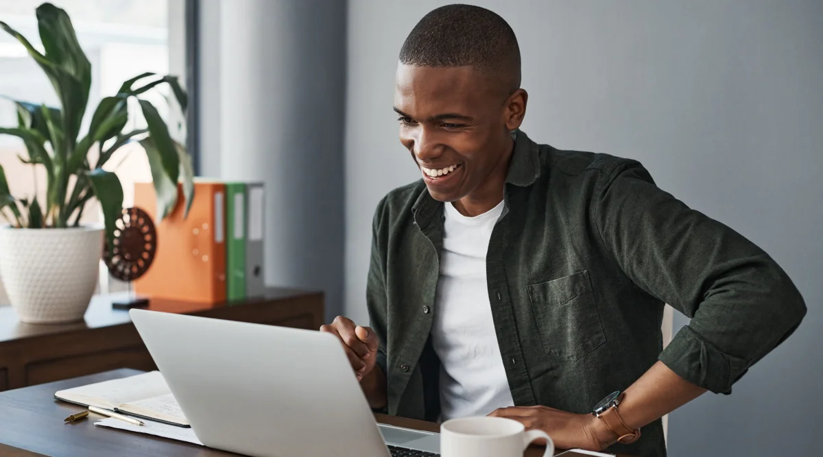 Man smiling at a laptop in a well-lit office