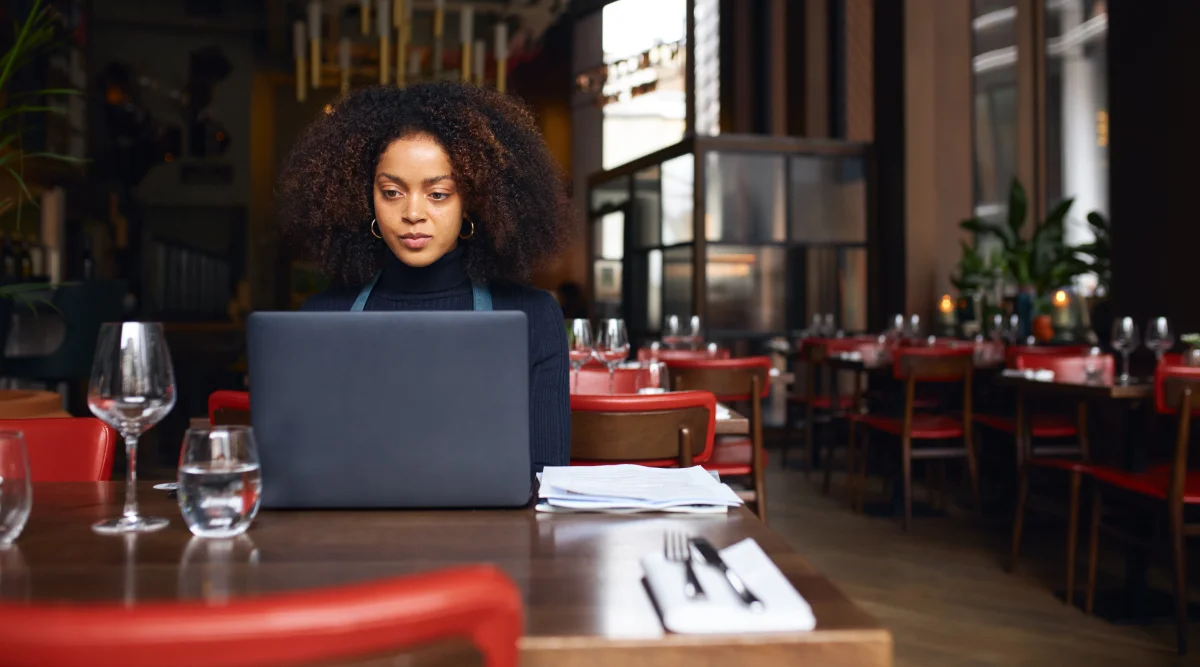 Woman works on laptop in her restaurant 