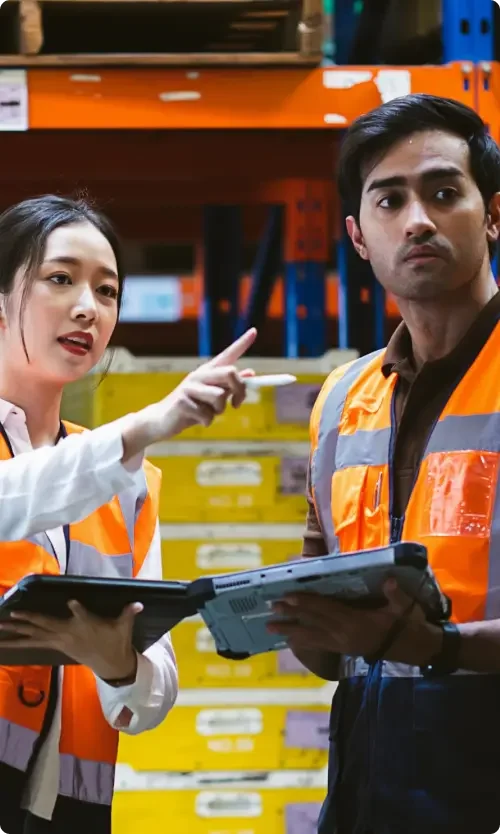 A male and a female independent contractor working together on tablets in a warehouse