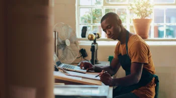 Artisan working at a desk with a laptop and tools