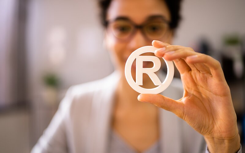 An image of a woman displaying a white 'registered trademark' symbol.