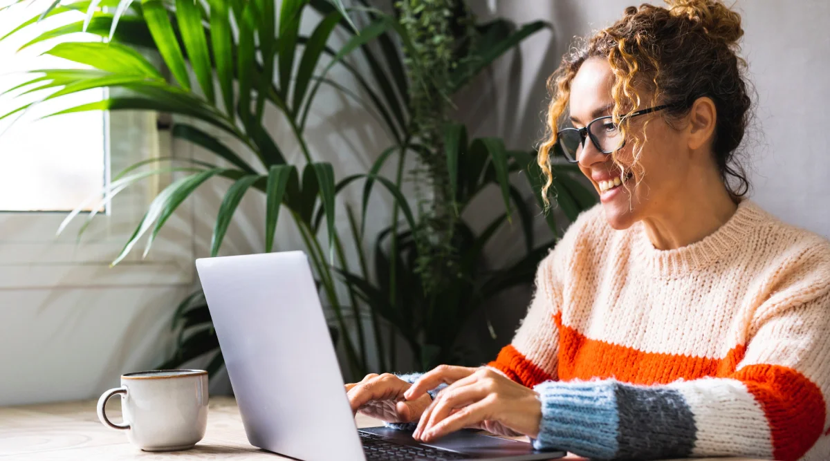 Woman in colorful sweater typing on laptop