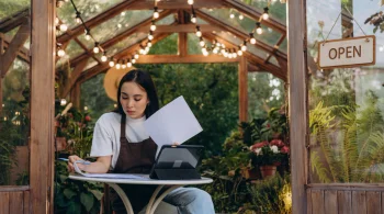 Woman in apron working on documents in a greenhouse