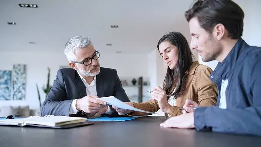 A couple sits with their attorney going over some paperwork.