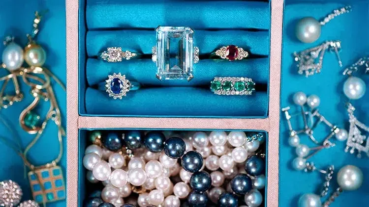 Close up of a jewelry box with rings, earrings, pearls, and more.