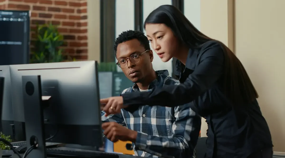 Man and woman sit at a desktop computer and research how to protect their product.