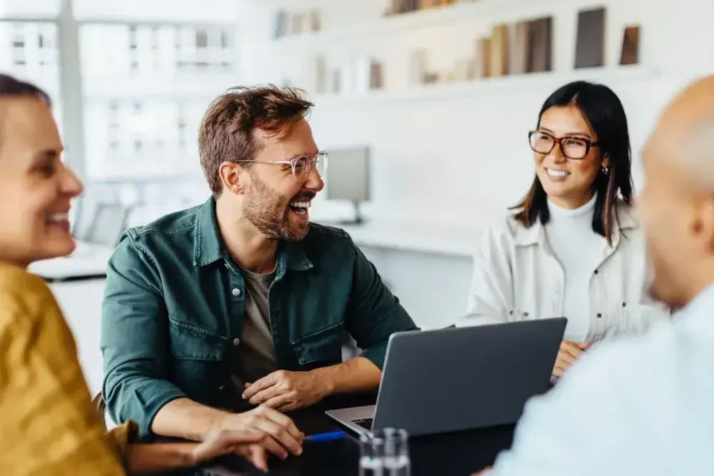 A group of business partners laugh at a conference table.