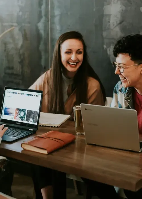 A consultant and an employee working together on laptops at a table