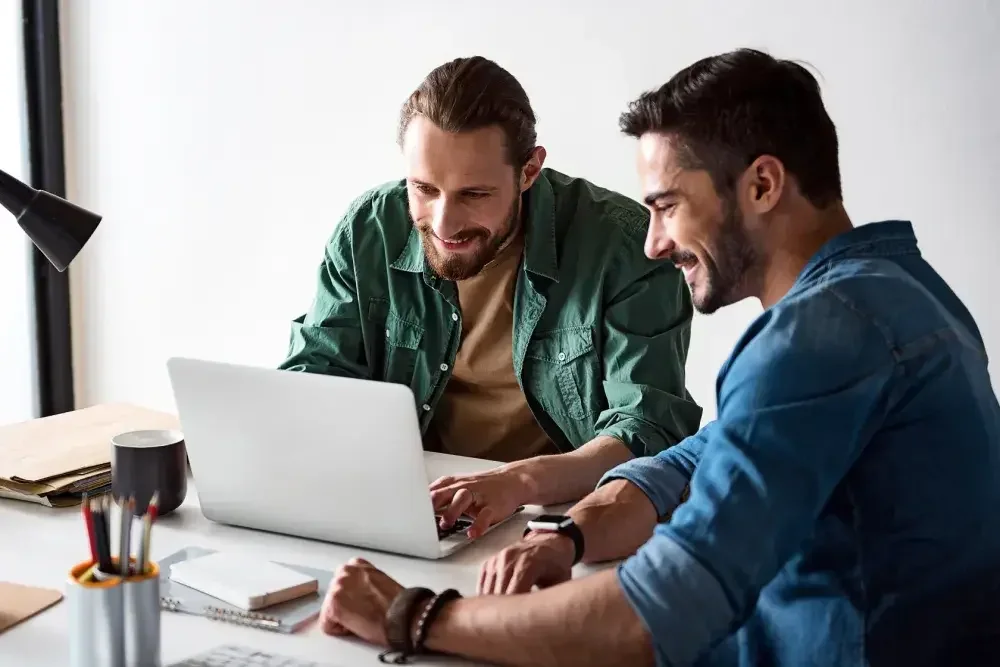 Two men seated at a table with an open laptop learn how to create a series LLC