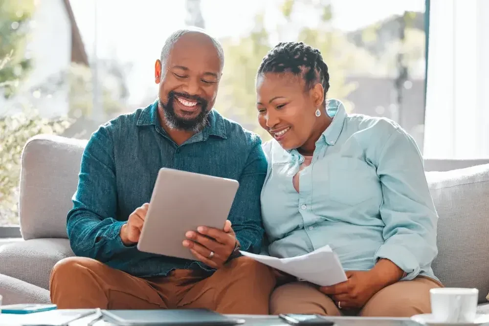 A couple seated on a couch reviews a last will on their iPad. Any adult over age 18 who is mentally competent enough to understand they are creating a will.