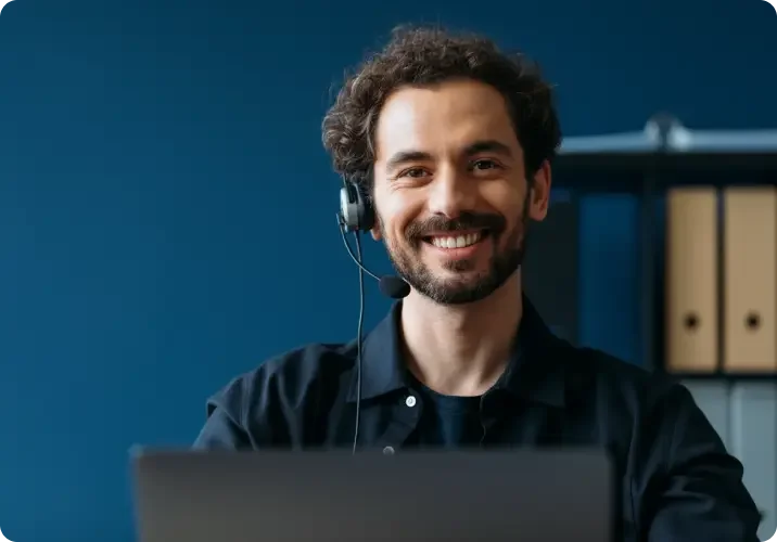 A beared, brown-haired man receives calls on a headset