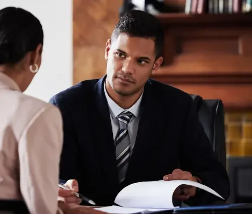 A male commercial real estate attorney sitting at a desk and providing legal guidance to a client sitting in front of him