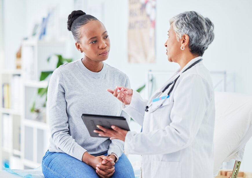 An image of a doctor holding an iPad and explaining the different types of healthcare directives to a patient.