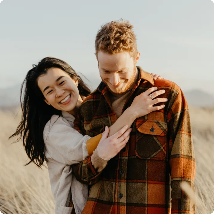 An asian woman and white man in a field enjoying a fall day