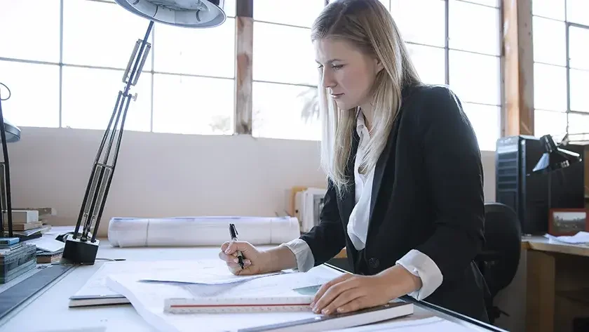 Young professional woman in office, reviewing notes on how to get a business license in Alabama.