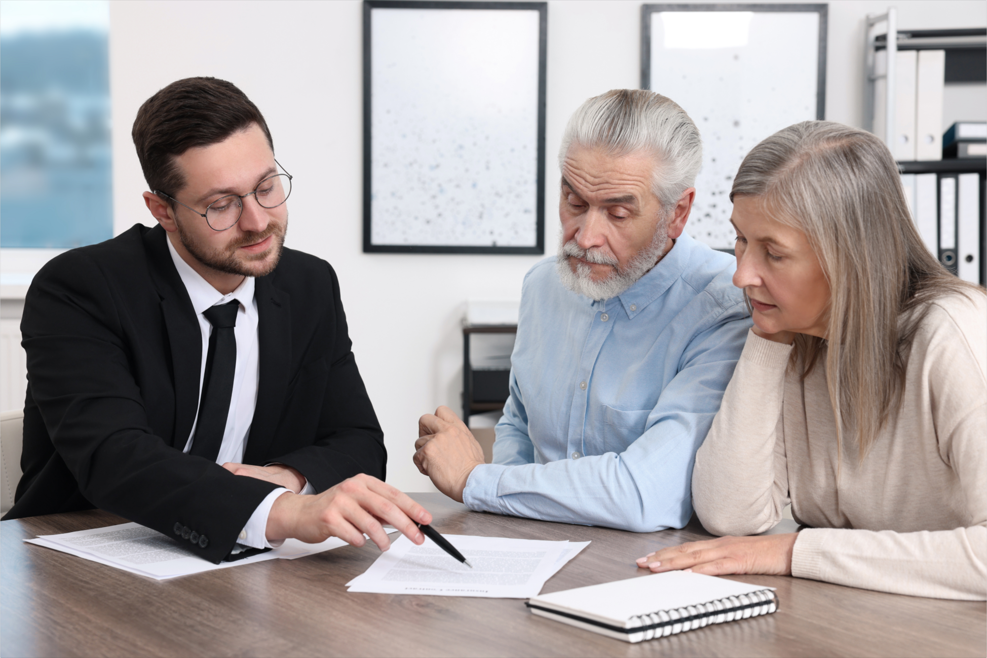 An attorney explains the duties of the trustor and trustee to an older couple in their office.