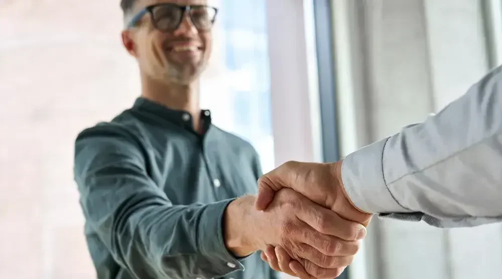 A man smiling and shaking hands with another man after choosing LegalZoom's estate planning services.