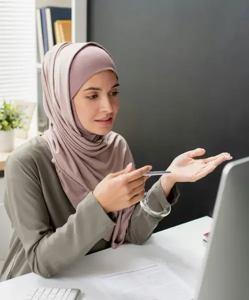 An adult woman sitting at a desk in front of a computer updating miscellaneous online accounts, such as utility, insurance, and membership accounts, following a legal name change